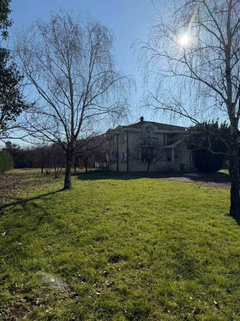View of a house with a spacious lawn and trees on a sunny day.