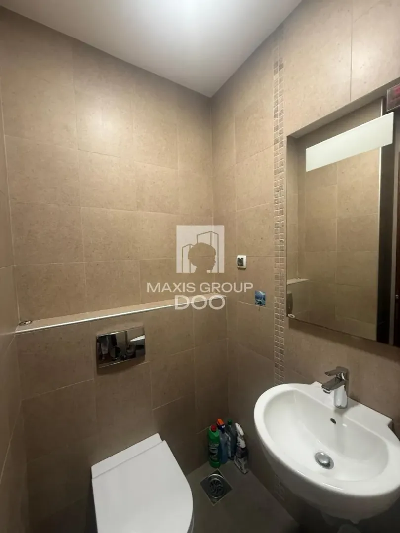 Small bathroom tiled in beige with a washbasin and toilet.