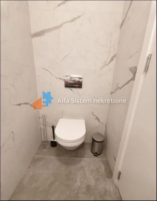 Smaller bathroom lined with ceramic tiles featuring a wall-hung toilet.