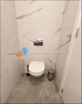 Smaller bathroom lined with ceramic tiles featuring a wall-hung toilet. - image 16