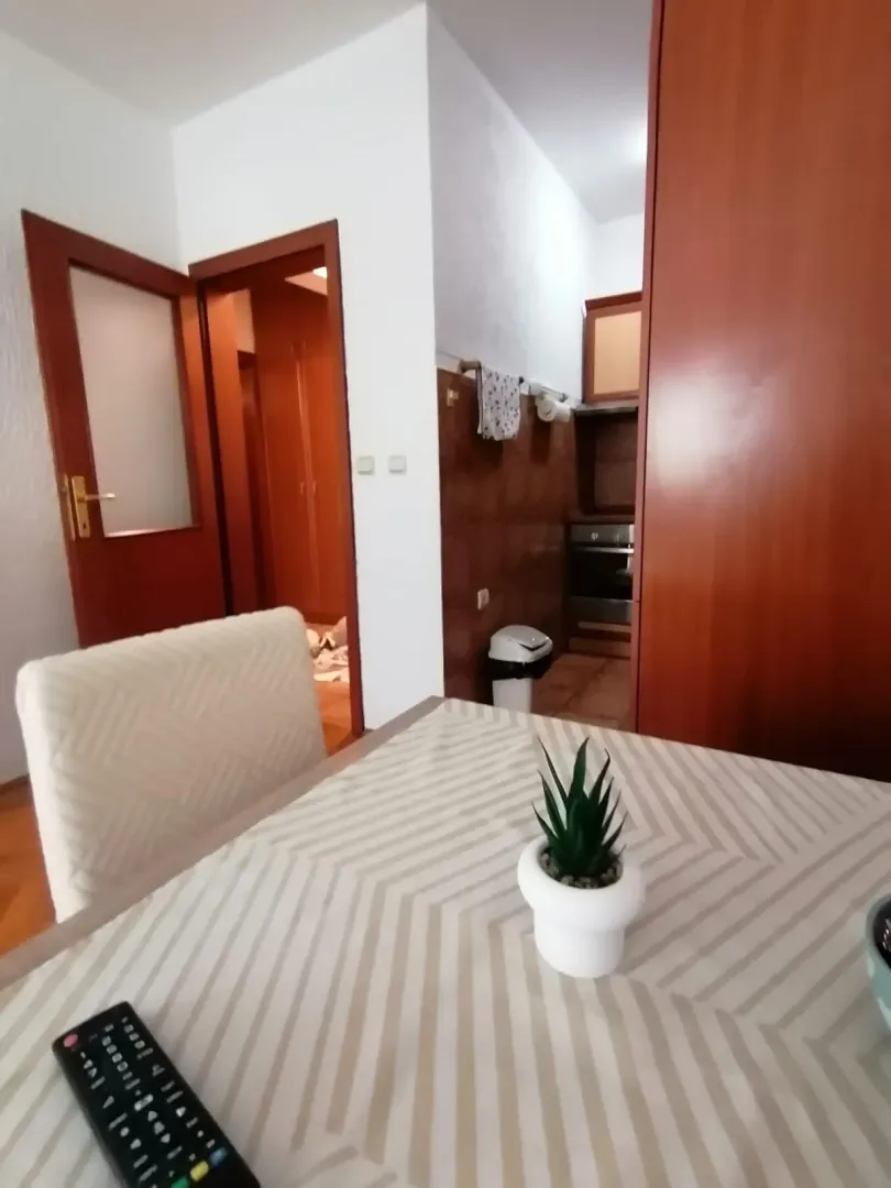 Trpezarija sa stolom i pogledom prema kuhinji i hodniku.