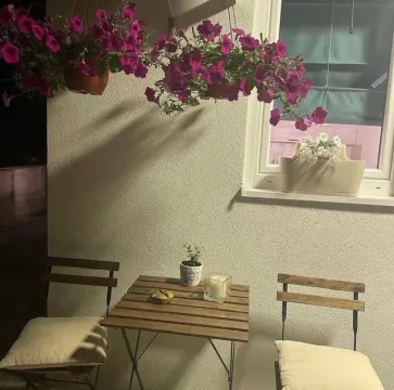 Small terrace with a wooden table, chairs, and decorative flowers. - image 8