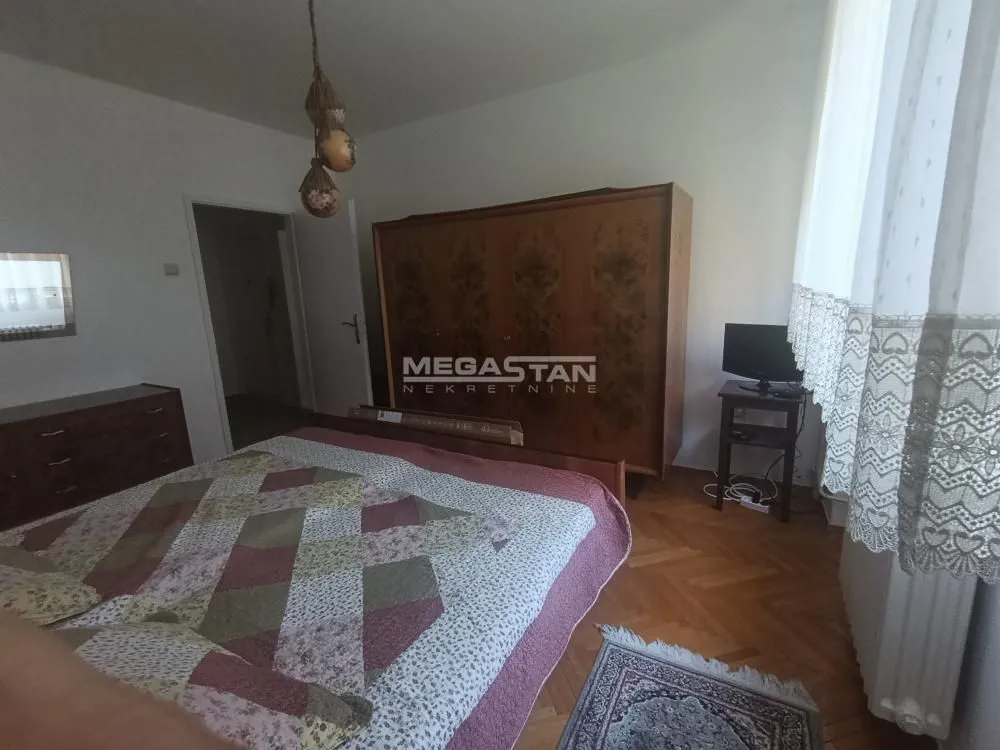 Bedroom with a double bed, wooden wardrobe, and parquet flooring.