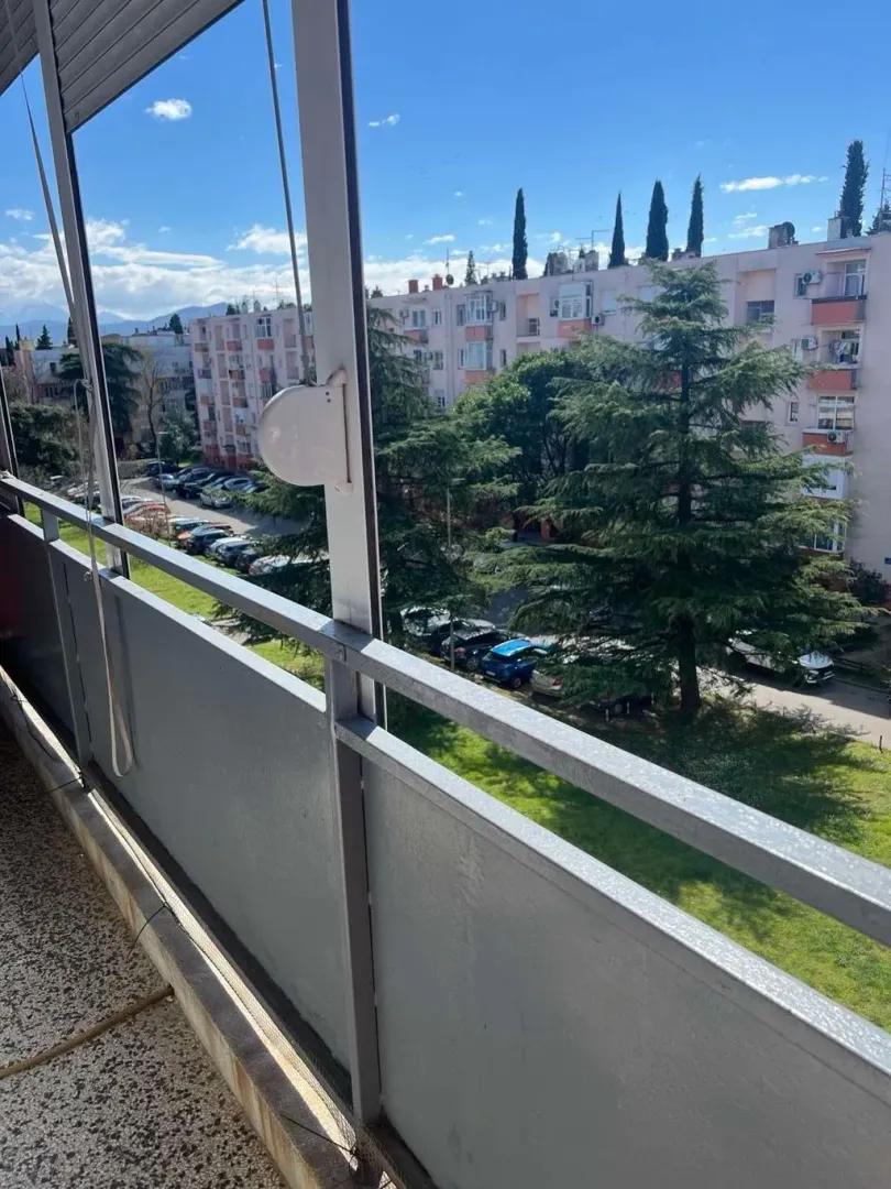 View from the balcony overlooking surrounding buildings, green areas, and parking.