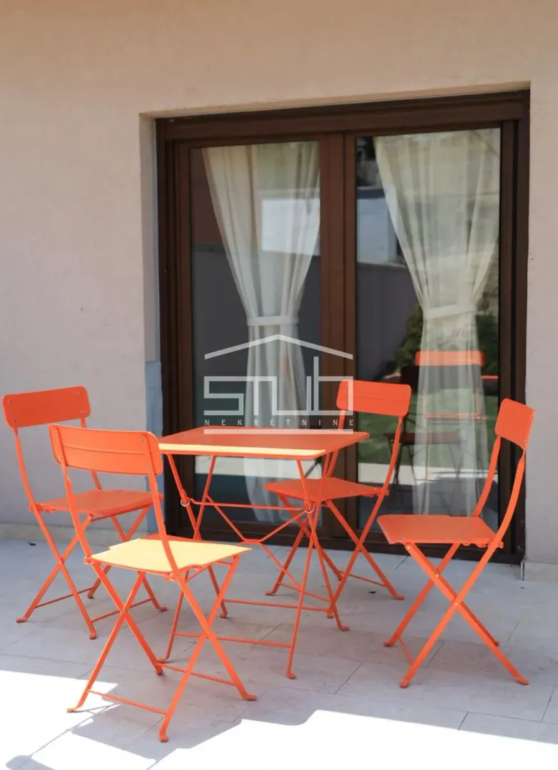Furnished terrace with an orange table and chairs in front of the balcony door.