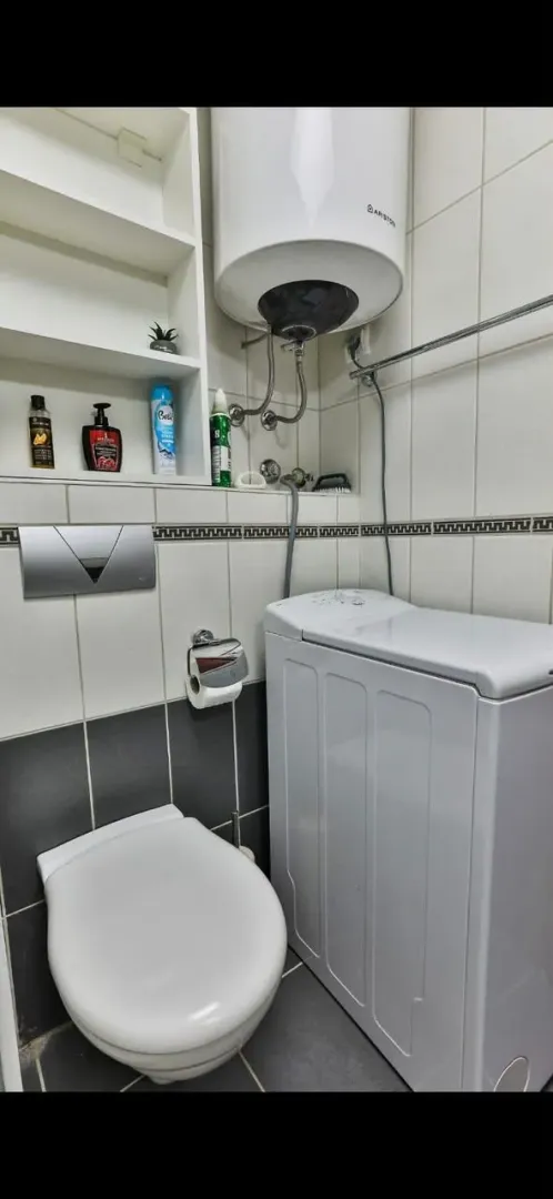 Small bathroom with toilet, washing machine, and water heater.