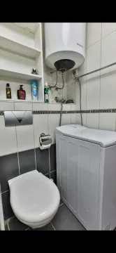 Small bathroom with toilet, washing machine, and water heater. - image 3