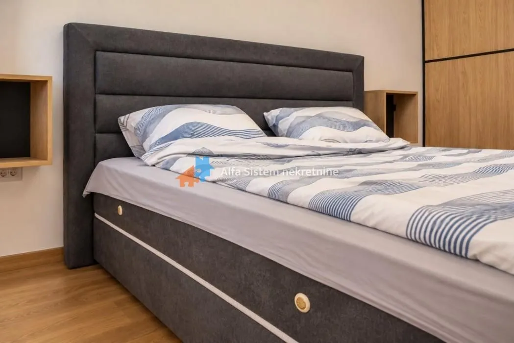 View of a double bed with a padded headboard in the bedroom.