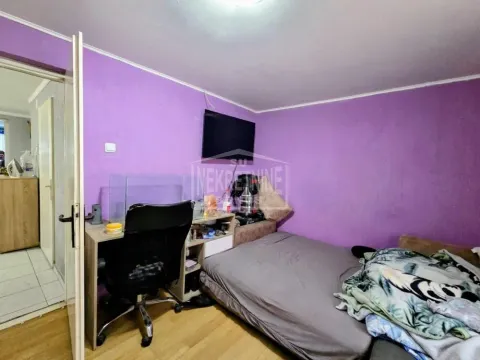 Manja spavaća soba sa krevetom, radnim stolom i televizorom na zidu. - image 3