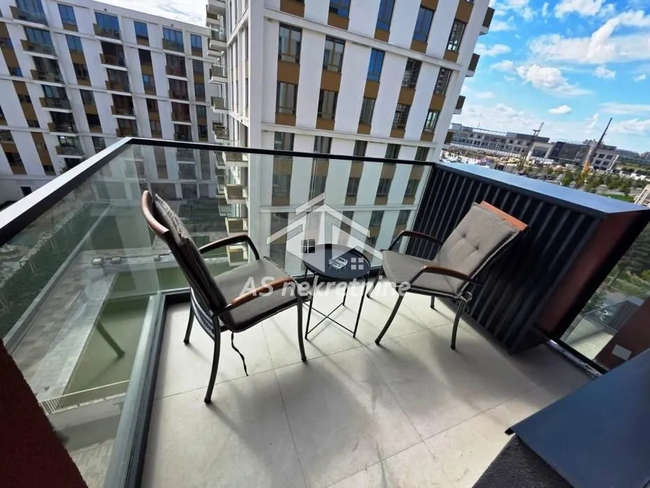 Furnished balcony with seating set and view of surrounding buildings.