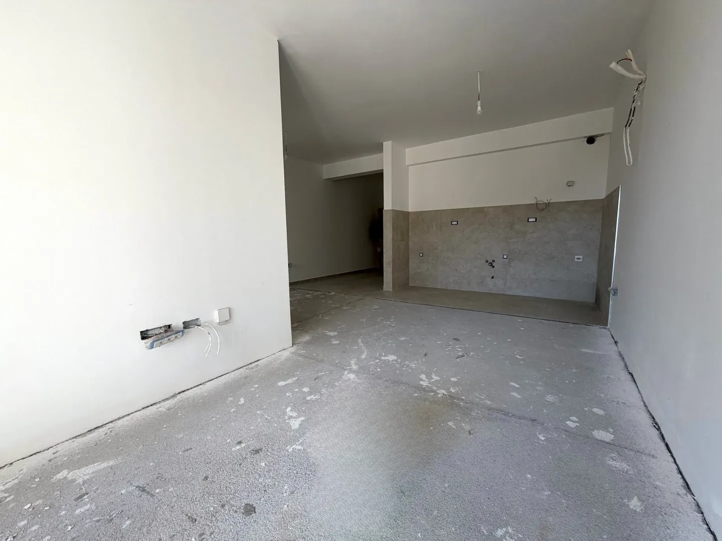 Neopremljena prostorija u izgradnji sa bijelim zidovima i keramičkim pločicama na zidu.
