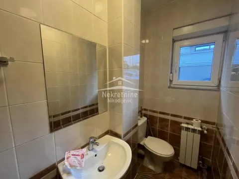 Smaller bathroom lined with ceramic tiles featuring a sink and toilet. - image 15