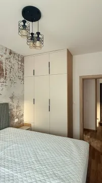 Uređena spavaća soba sa bračnim krevetom, garderoberom i modernim lusterom. - image 7