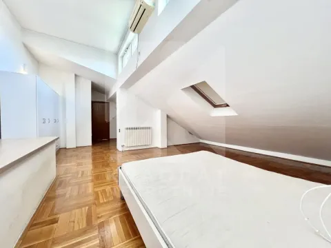 Attic bedroom with a bed, parquet flooring, and a skylight. - image 10