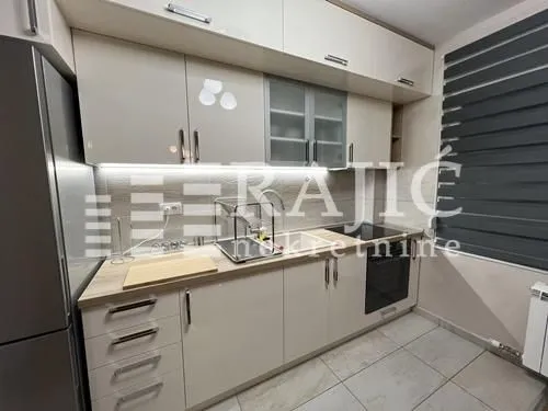 Modern kitchen with beige cabinets and built-in appliances.