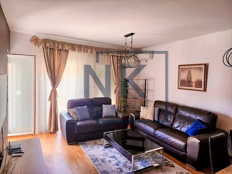 Spacious living room with dark leather sofas and a dining table.