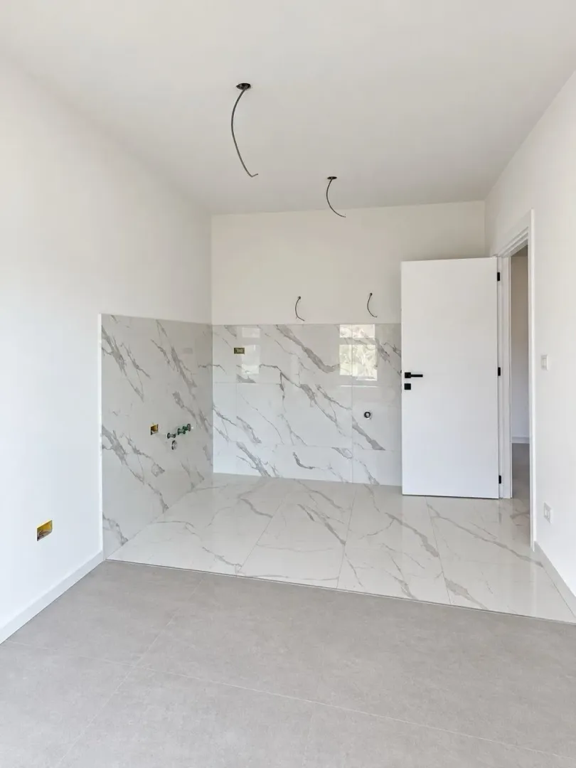 Nekororišćeni kuhinjski prostor sa mermernim pločicama i pripremljenim instalacijama.