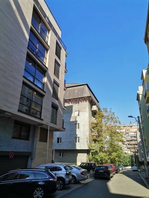 View of the street with parked cars and surrounding buildings.
