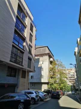 View of the street with parked cars and surrounding buildings. - image 10