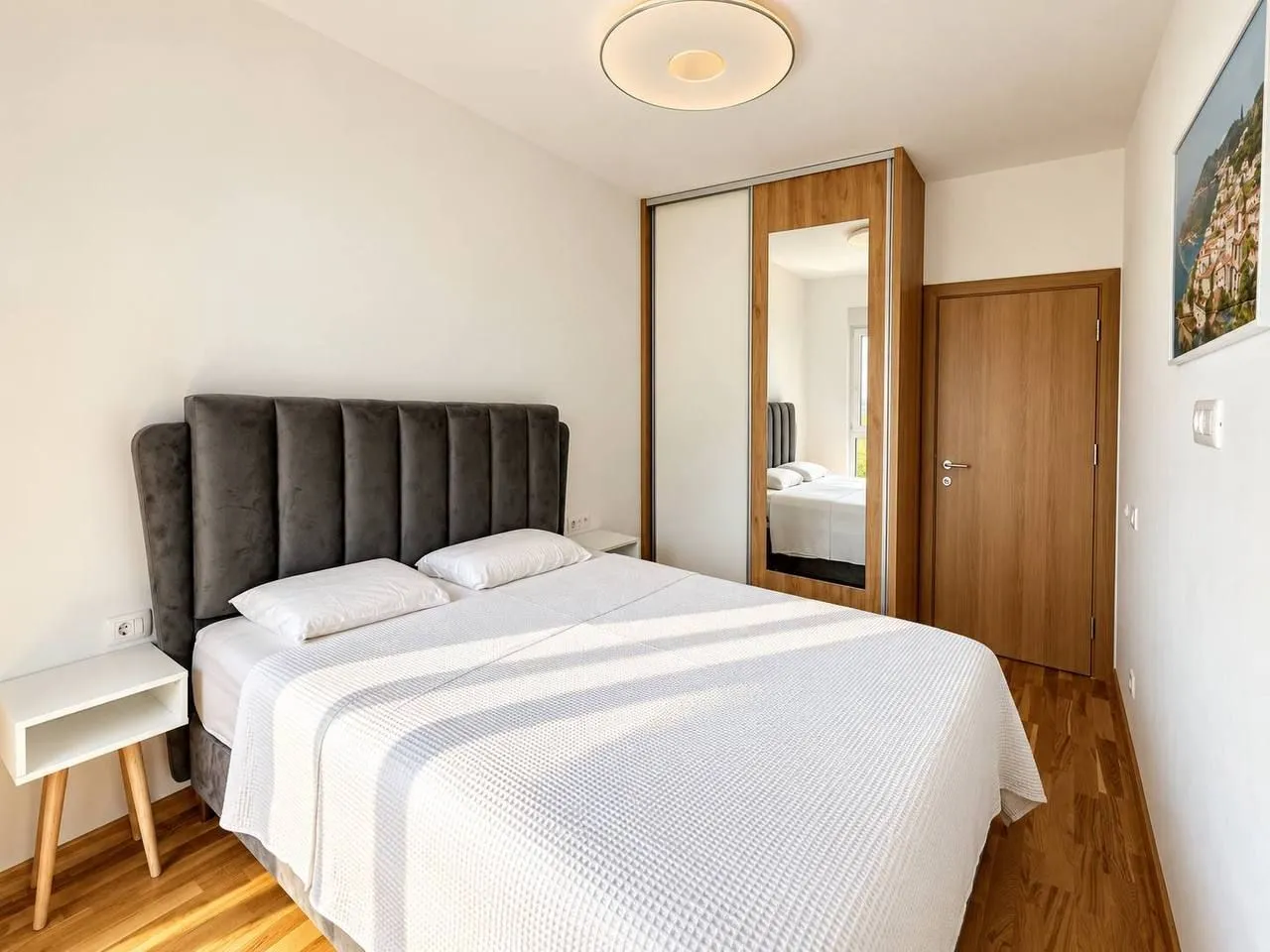 Furnished bedroom with a double bed, wardrobe, and wooden flooring.