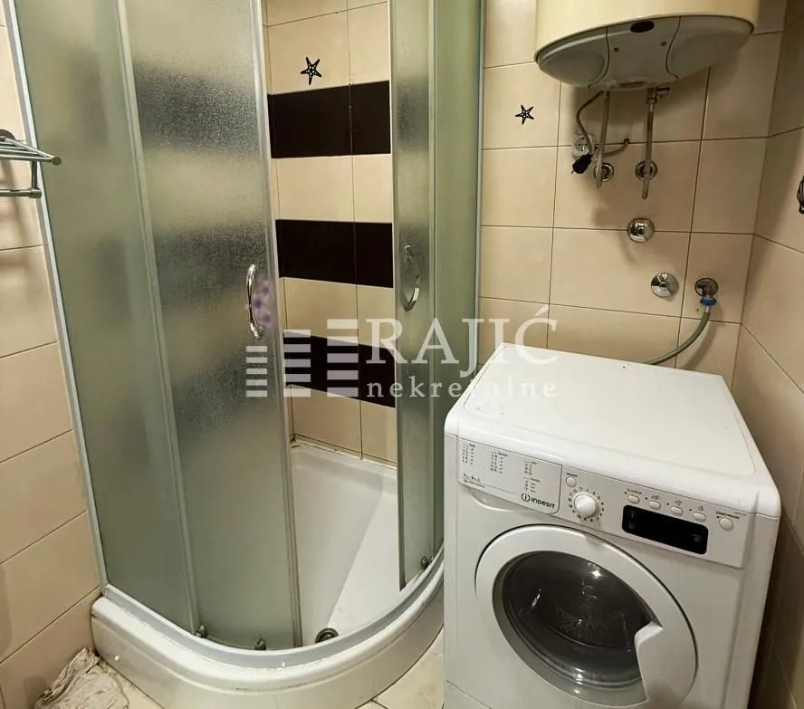 Small bathroom with a shower cabin and a washing machine.