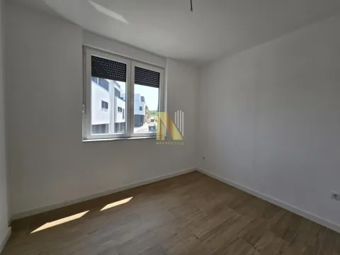 Prazna soba sa belim zidovima, drvenim podom i prozorom. - image 5