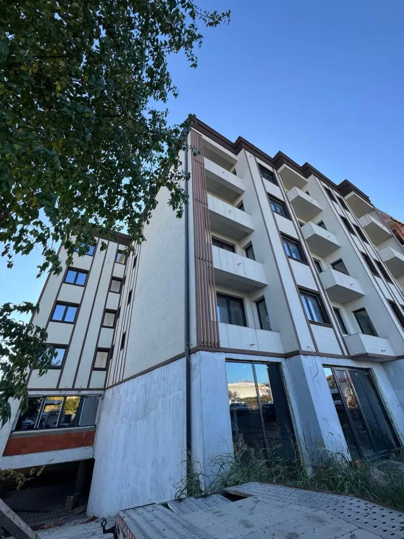 Pogled na spoljašnjost stambene zgrade sa balkonima i uređenom fasadom.