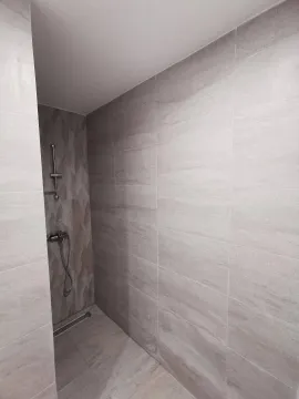Pogled na moderno uređeno kupatilo sa tuš kabinom obloženom sivim pločicama. - image 4