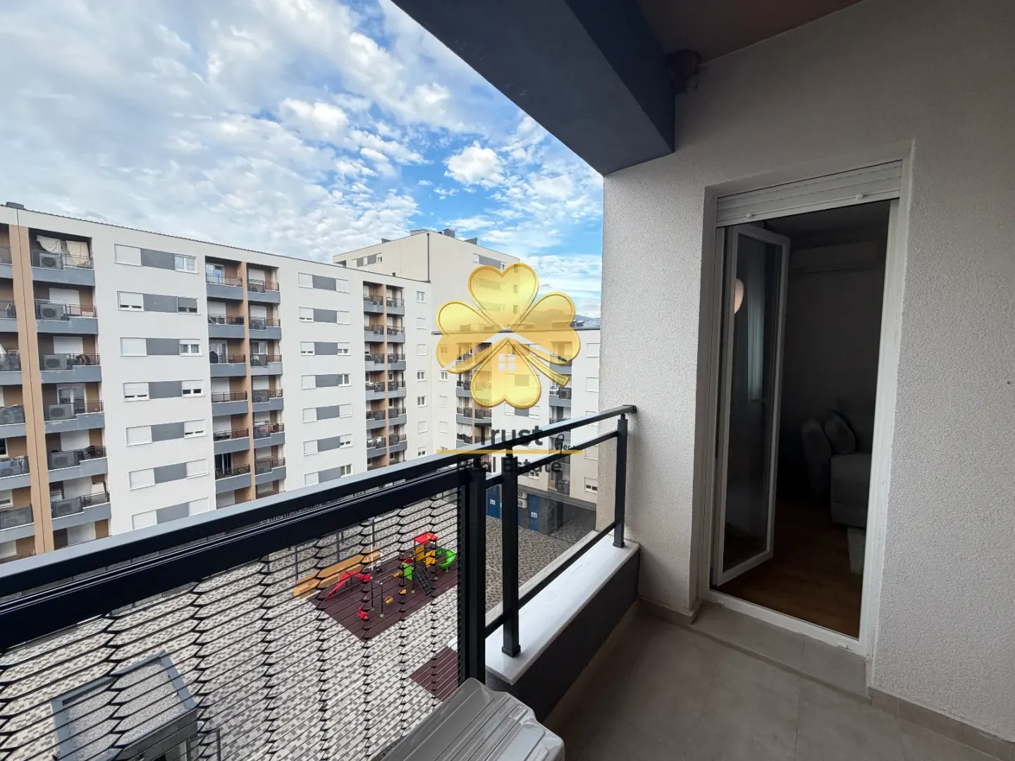 Balcony with a view of surrounding buildings and a playground.