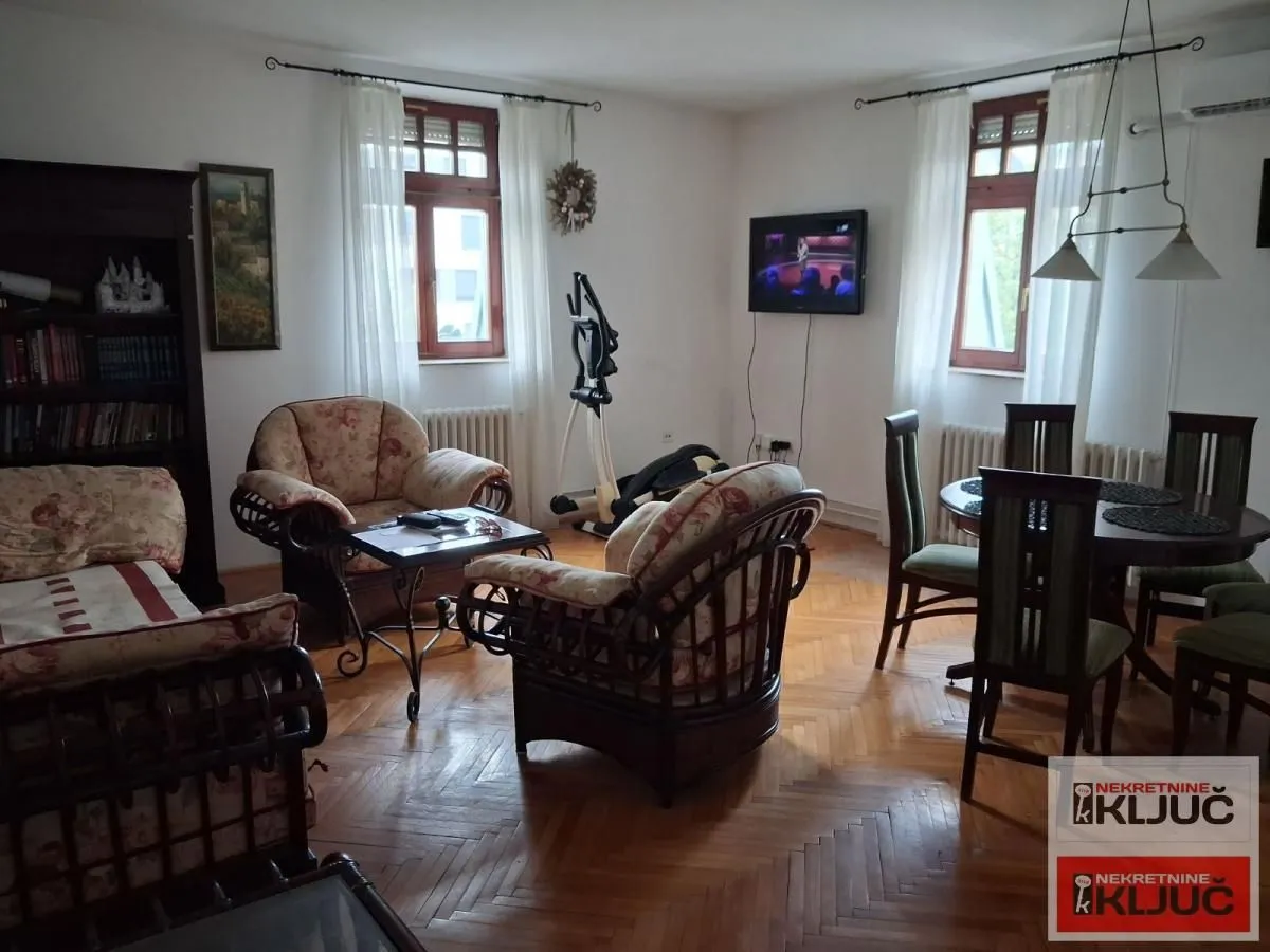 Dnevna soba sa garniturom za sedenje i trpezarijskim stolom.