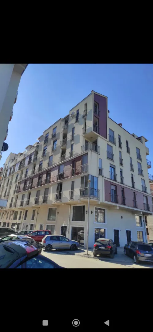 Exterior view of an apartment building with balconies and parking.