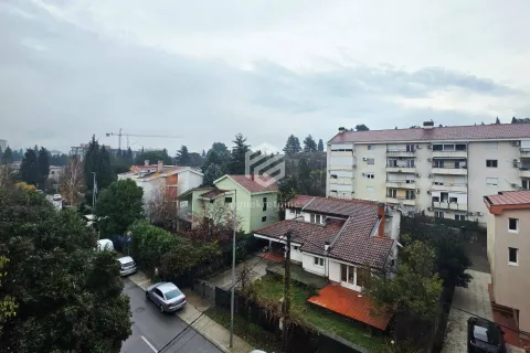 View from the window overlooking surrounding buildings and greenery. - image 6