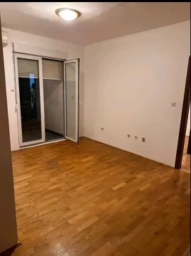 An empty room with wooden parquet flooring and balcony doors. - image 5