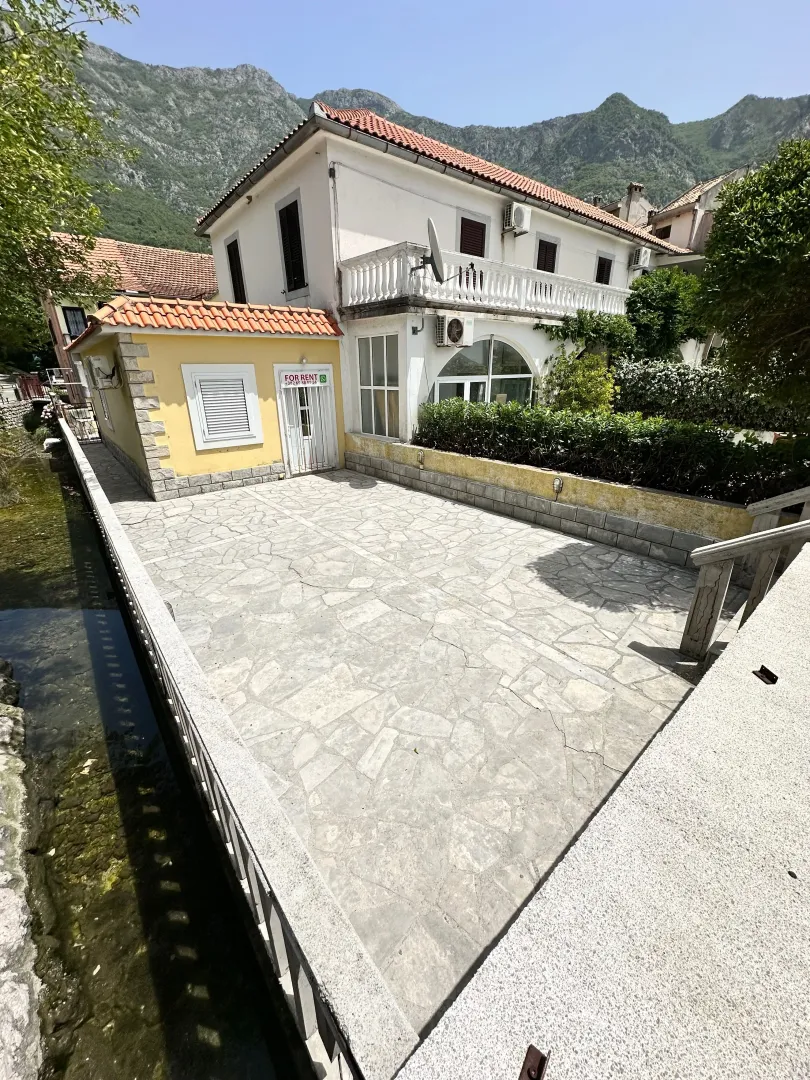 View of the courtyard and house facade with mountains in the background.