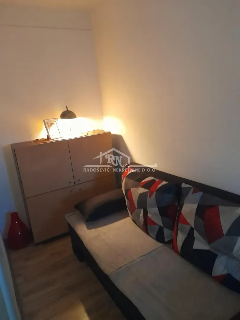 Small living room with a sofa and a cabinet with a lamp.