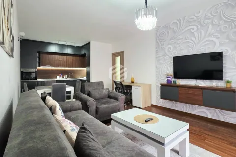 Living room with a sofa, TV, and kitchen in the background. - image 14