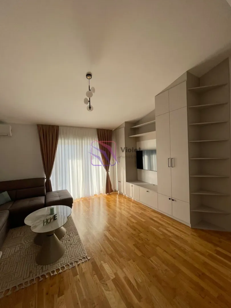 Dnevna soba sa garniturom, klub stolićem i ugradnim ormarima.