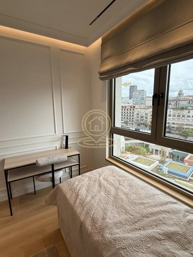 Furnished bedroom with a bed, desk, and city view.