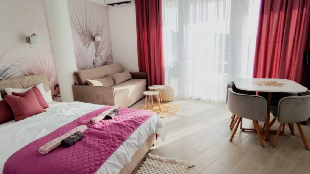 Furnished bedroom with a double bed, sofa, and dining table.