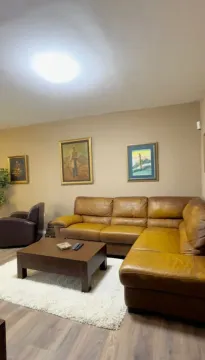 Living room with a leather sectional sofa, coffee table, and wall paintings. - image 3