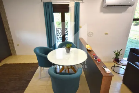 Dining area with a round table and blue armchairs next to balcony doors. - image 18