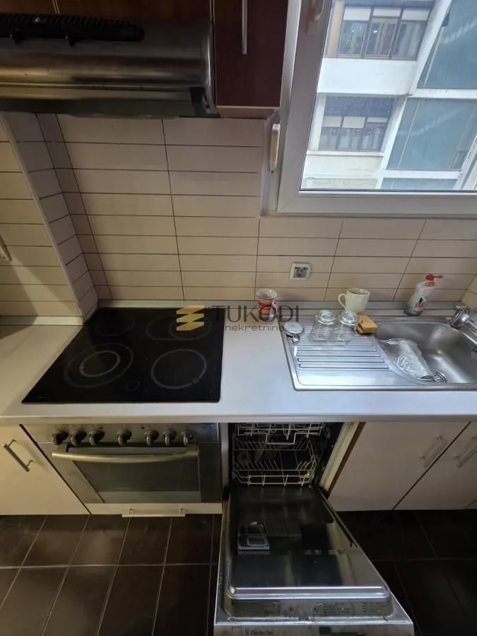 View of a kitchen section with a ceramic hob, sink, and an open dishwasher.
