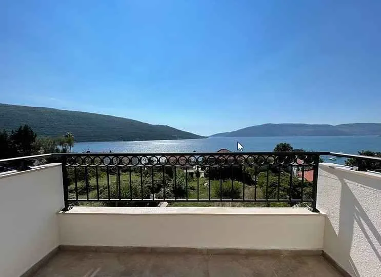 Balkon sa metalnom ogradom i pogledom na more i planine.