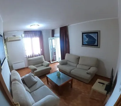 Svijetla dnevna soba sa udobnom garniturom za sjedjenje i drvenim klub stolom. - image 2