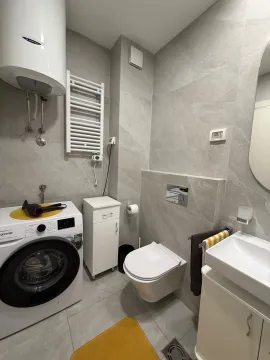 Savremeno opremljeno kupatilo sa veš mašinom i keramičkim pločicama u sivim tonovima. - image 10