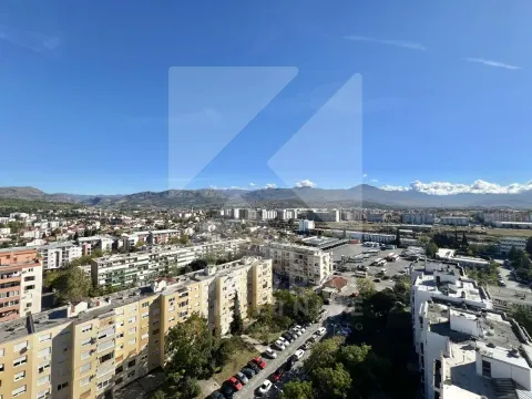 Pogled iz visine na gradski pejzaž i planine u pozadini. - image 6