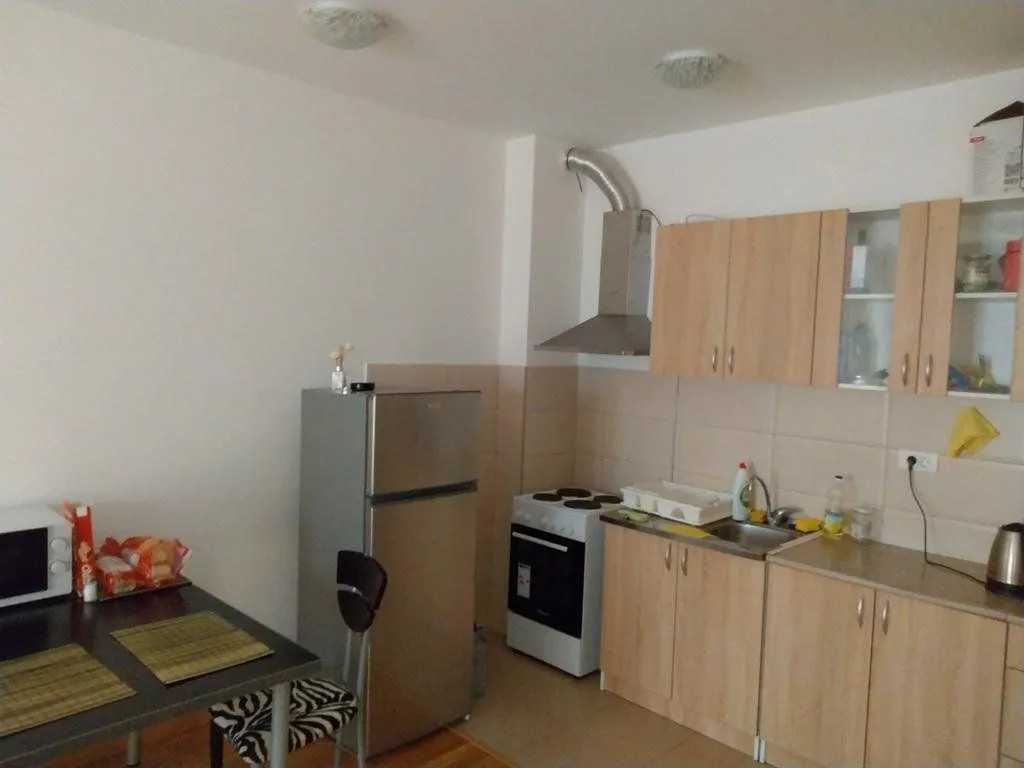 Small kitchen with wooden cabinetry, refrigerator and a dining table.