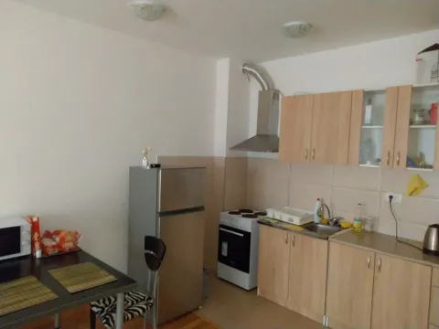 Small kitchen with wooden cabinetry, refrigerator and a dining table. - image 7
