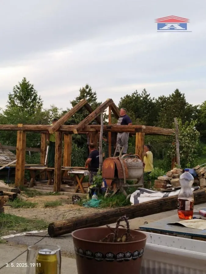 Workers are carrying out construction work on a wooden structure of a building in the yard.