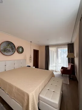 Spacious bedroom with a double bed, armchair, and balcony access. - image 3